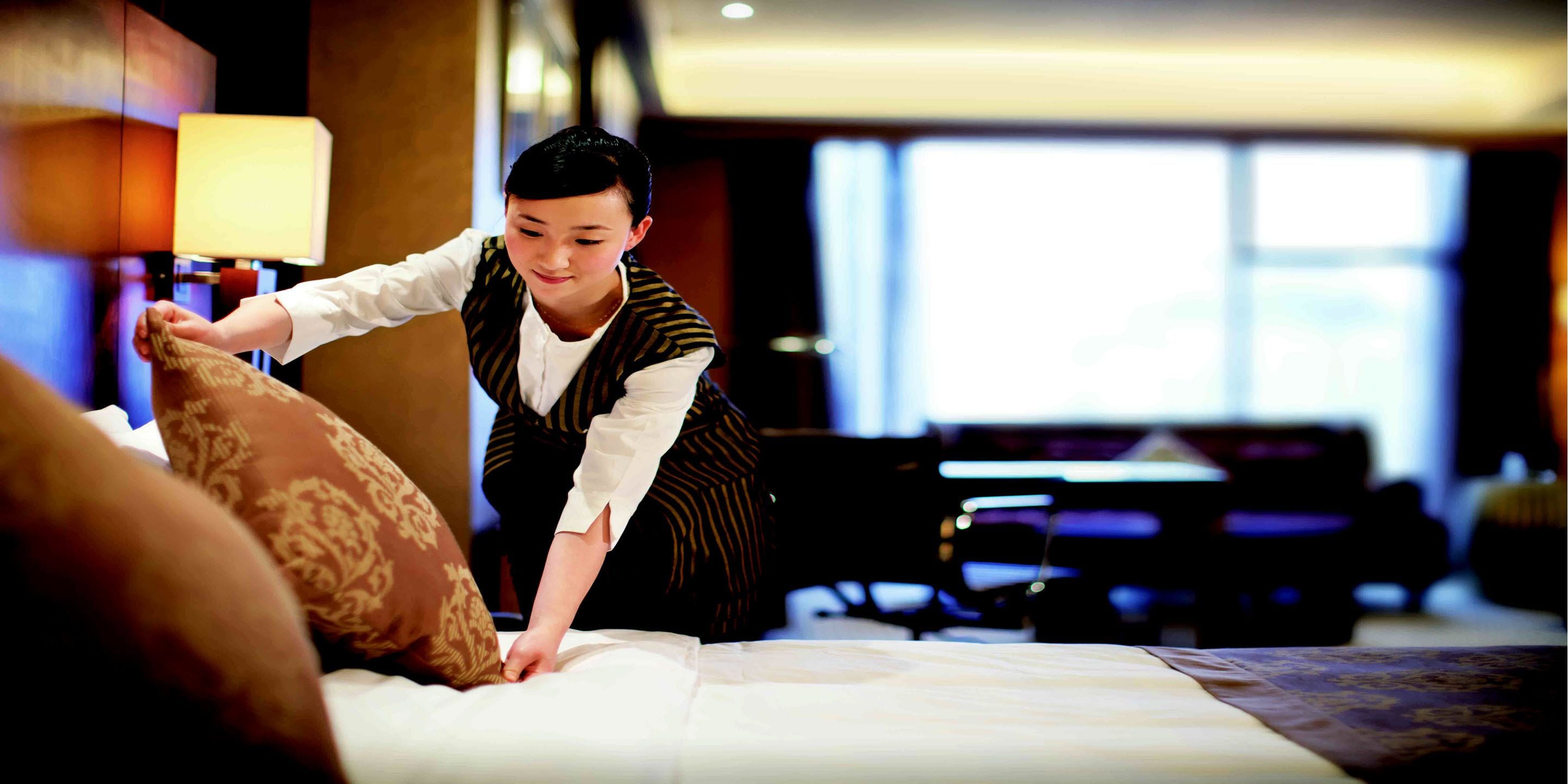 A hotel room with a neatly made bed, a lamp, and a view of the room's interior.