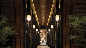 A hallway with wooden paneling, recessed lighting, and potted plants.