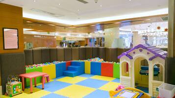 A children's play area with colorful play structures, a ball pit, and a small seating area.