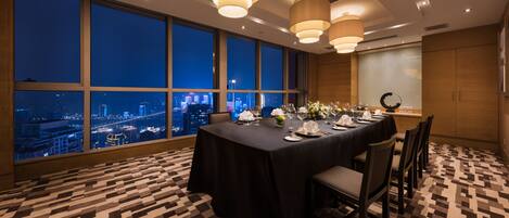 A conference room with a city view, large windows, and a table set for a meeting.