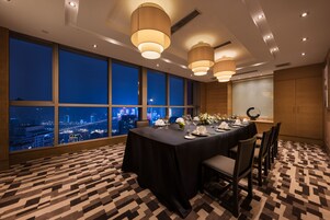 Un salón de conferencias con vista a la ciudad, amplias ventanas y una mesa dispuesta para una reunión.