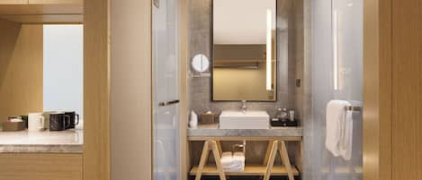 A modern bathroom with a glass shower enclosure, a wooden vanity, and a large mirror.