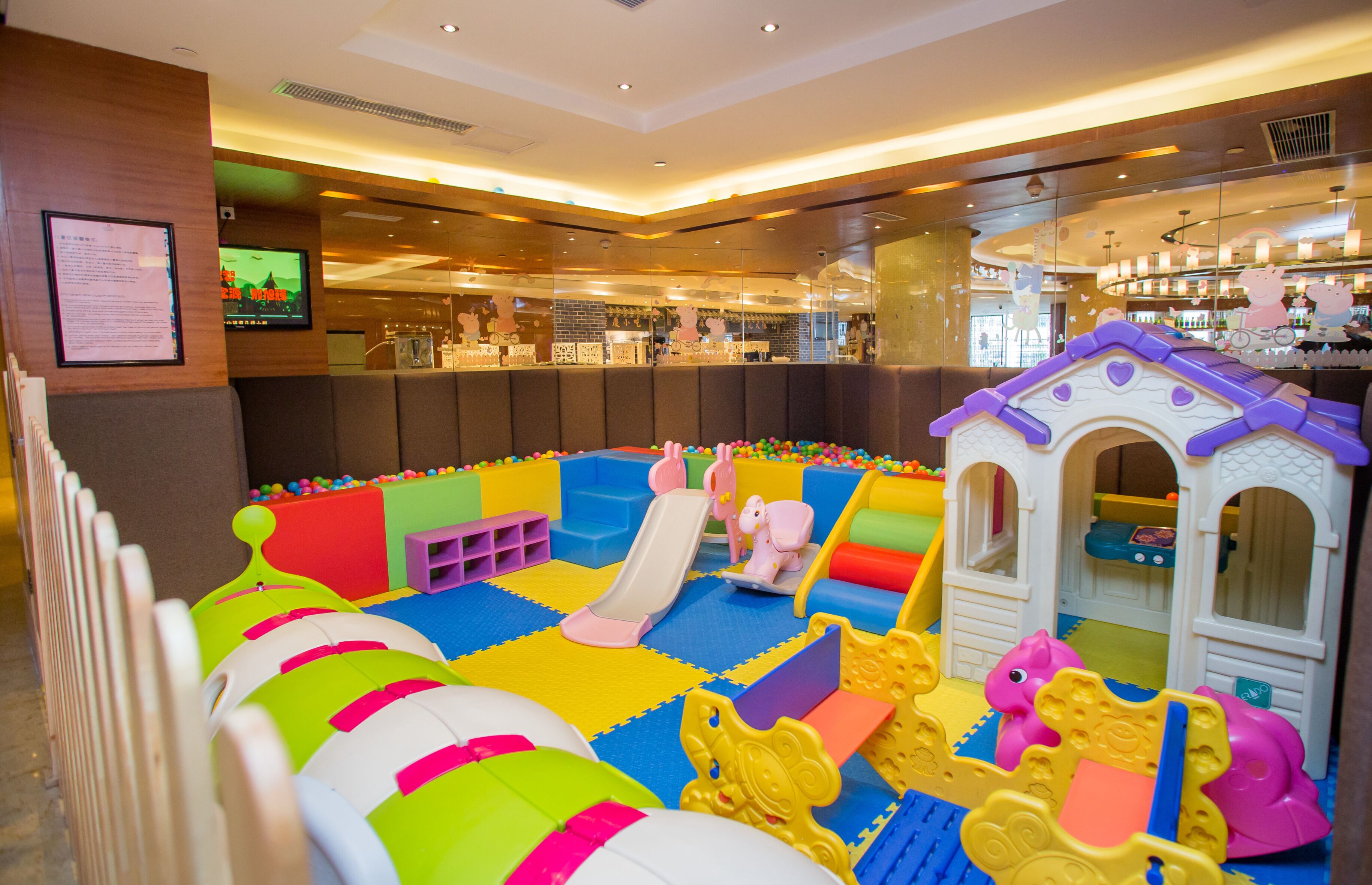 Un espace de jeux pour enfants avec un toboggan, une piscine à balles et des structures de jeu.