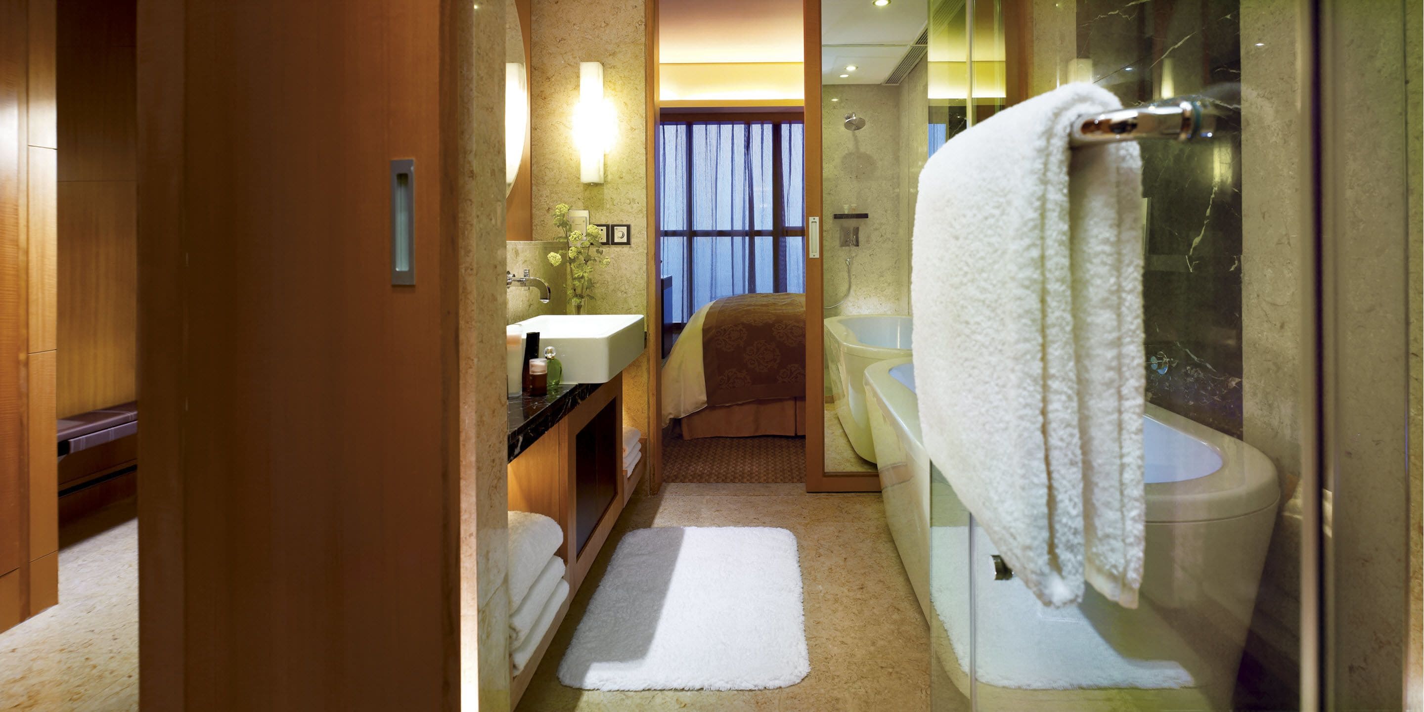 A hotel bathroom with a shower, toilet, sink, and a large mirror.