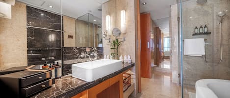 Un baño moderno con un espejo grande, un lavamanos blanco y una zona de ducha con paredes de vidrio.