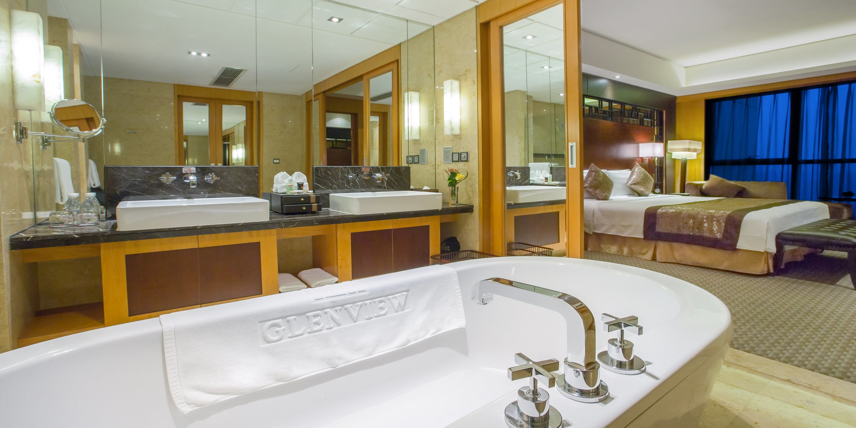 Un baño de hotel con una bañera grande, dos lavamanos y un espejo.