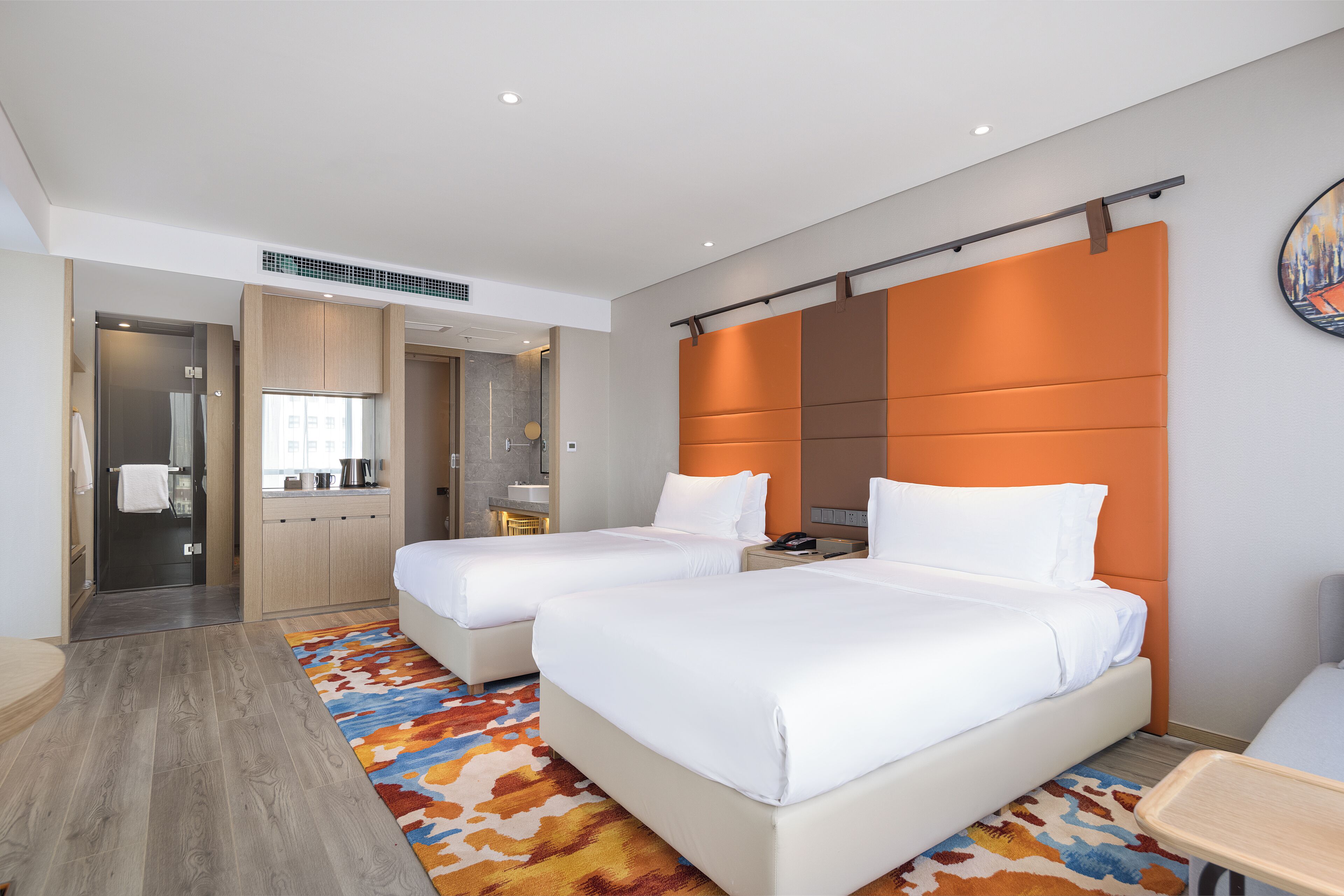 A hotel room with two beds, a desk, a bathroom, and a shower area.