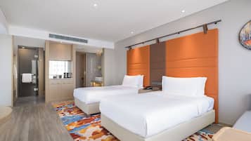 Ein Hotelzimmer mit zwei Betten, einem Schreibtisch, einem Badezimmer und einer Duschkabine.