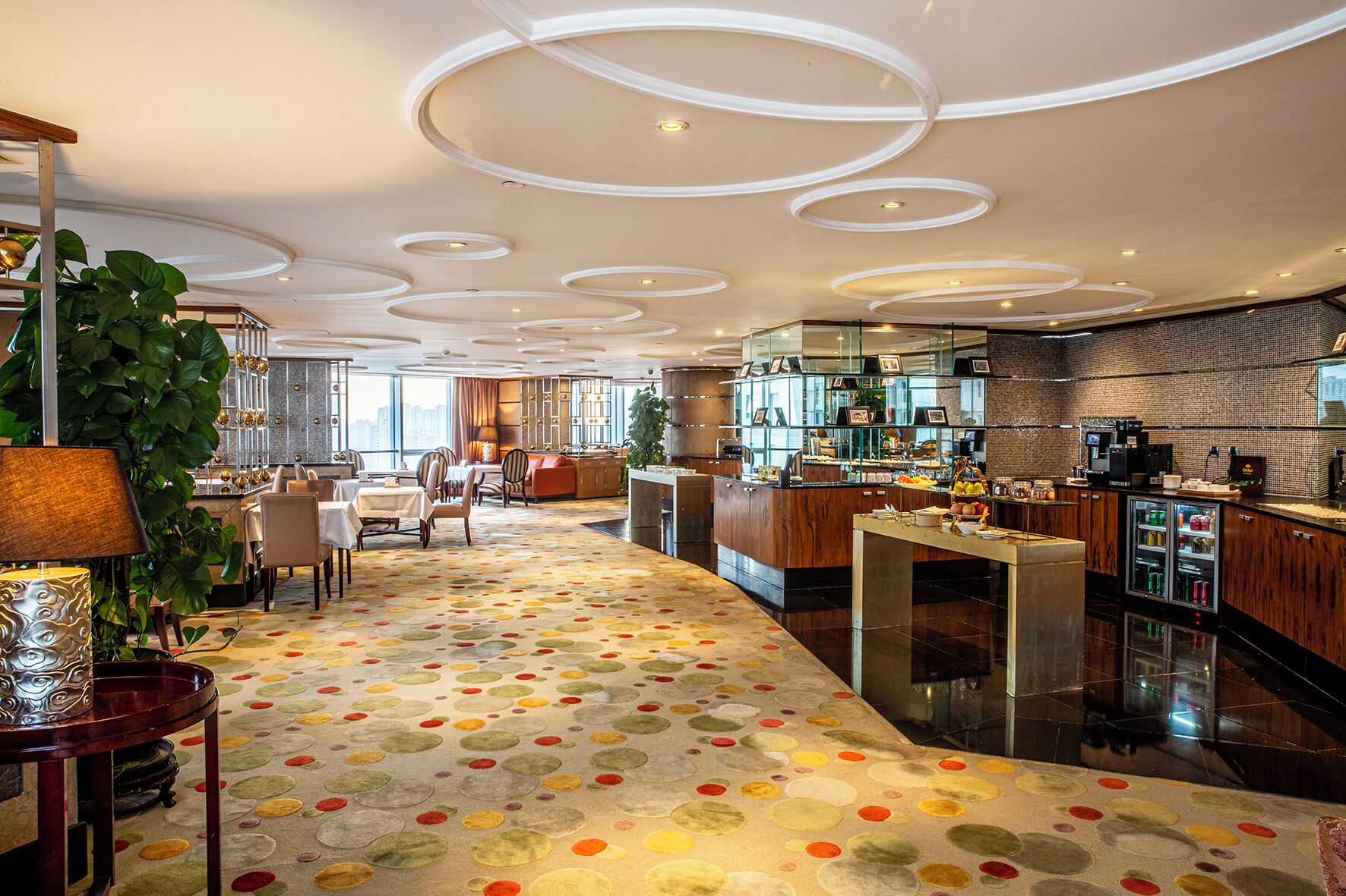 Un hall d’hôtel moderne doté d’un espace salon central, d’un bar et d’un coin cuisine.