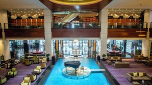 A spacious lobby with a central pool, multiple seating areas, and a second-floor balcony with a view of the pool. - Crowne Plaza Wuxi City Center by IHG (Wuxi)