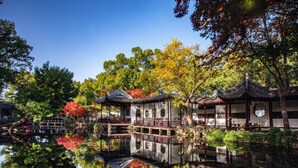 A traditional building with a reflection in the water, surrounded by trees and a clear sky. - Crowne Plaza Wuxi City Center by IHG (Wuxi)