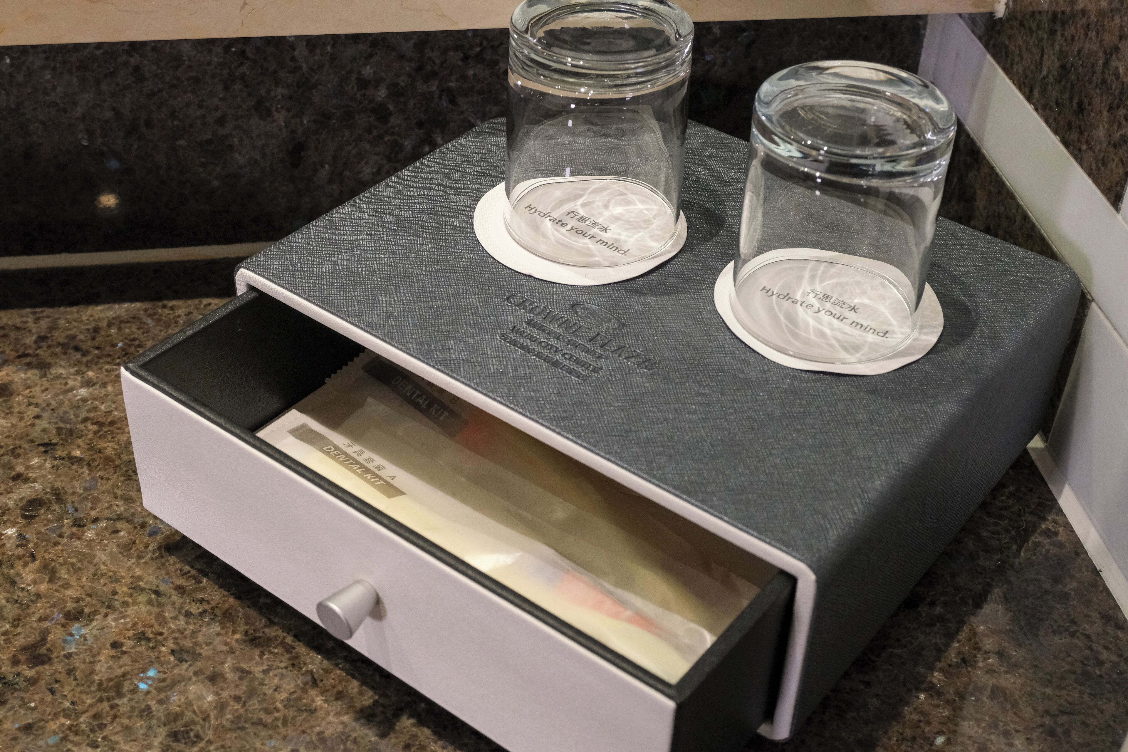 Un cajón con una caja de pañuelos y un tarro de vidrio con un posavasos sobre una superficie texturizada.