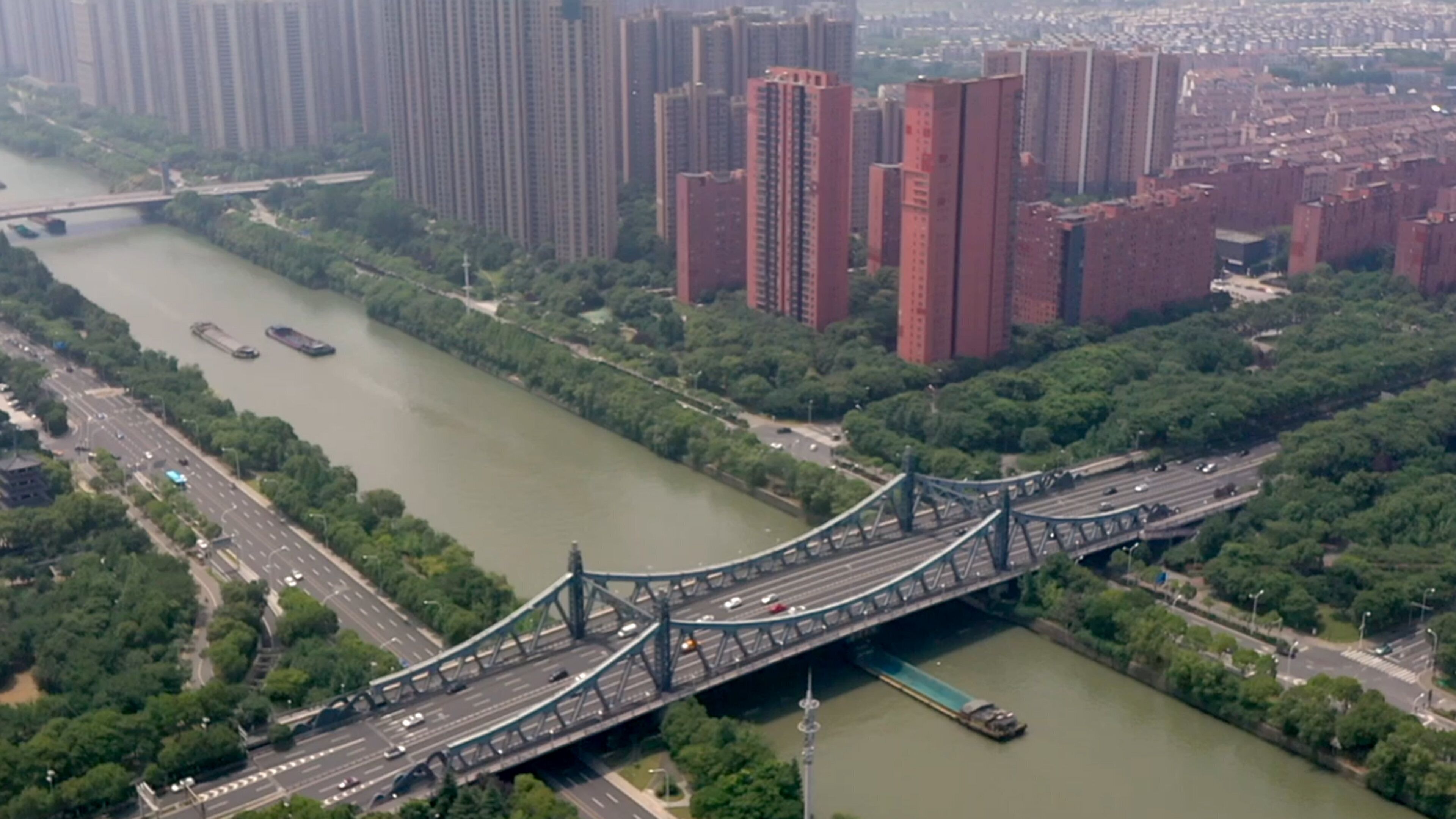 Un puente sobre un río, con edificios altos y áreas verdes aledañas.