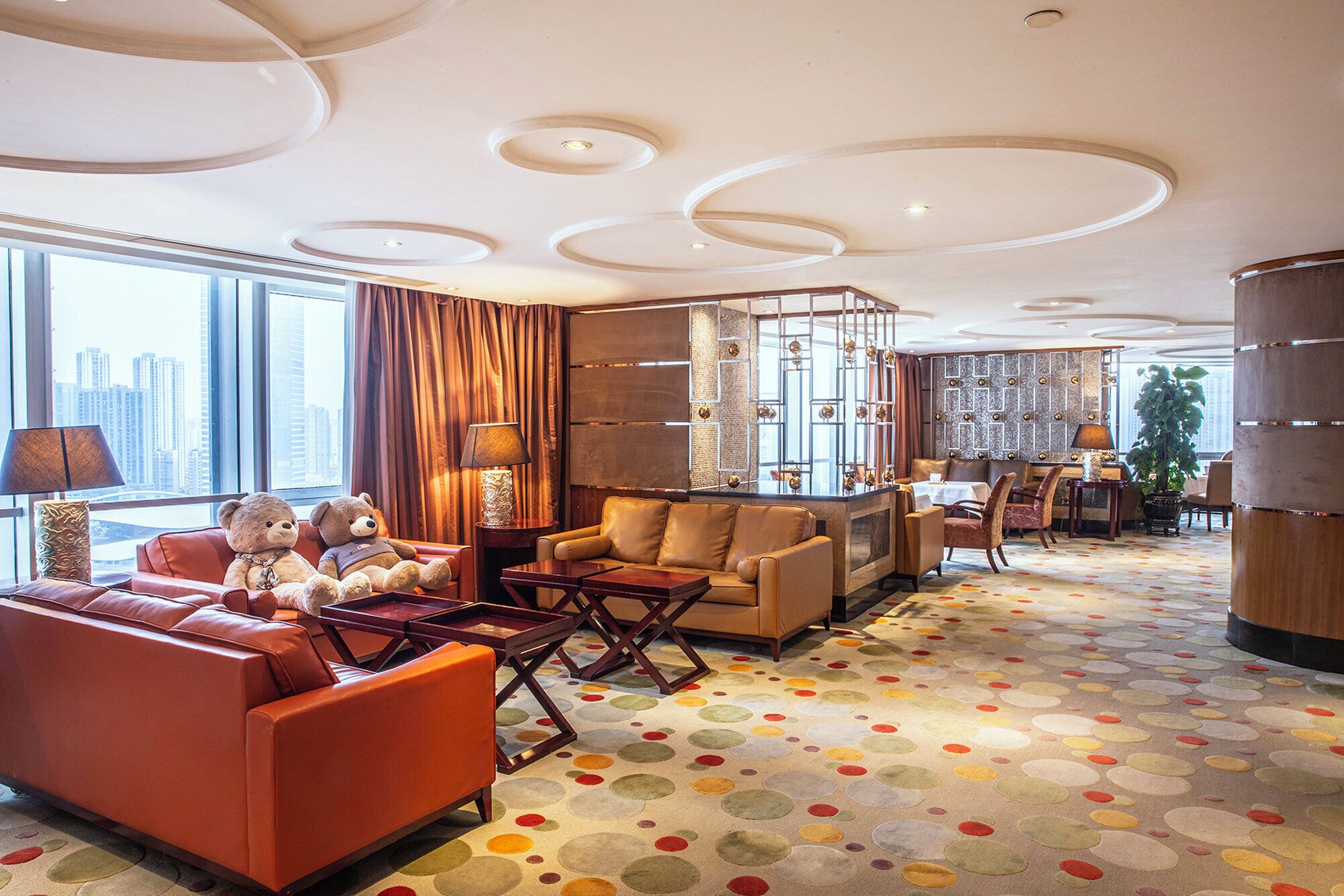 Un moderno hall de hotel con sofás de cuero, una mesa de centro, un comedor y un amplio ventanal con vistas a la ciudad.