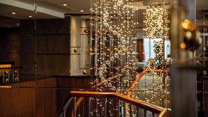 A staircase with a wooden handrail and a decorative light fixture with hanging crystals. - Crowne Plaza Wuxi City Center by IHG (Wuxi)