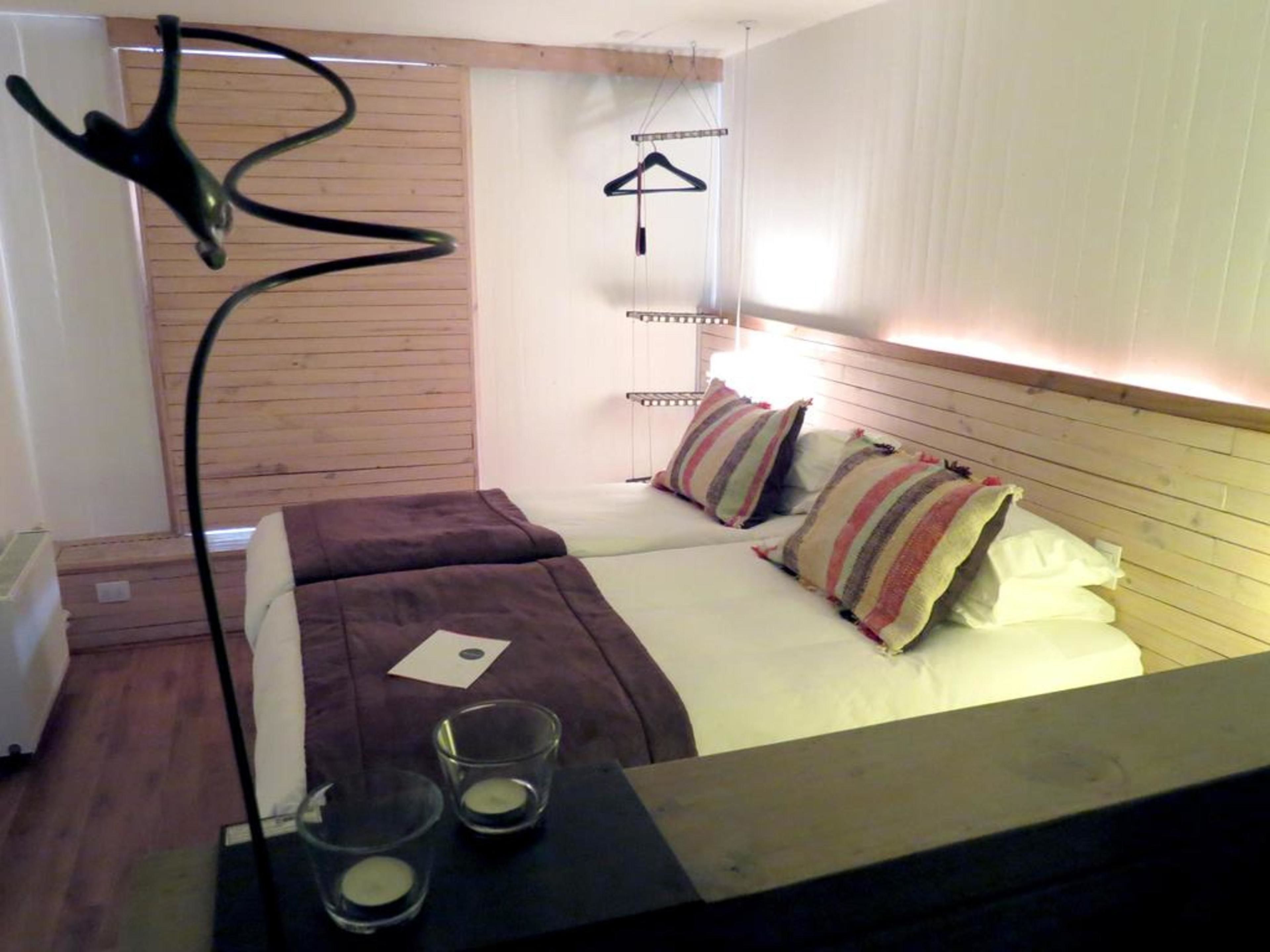 Un dormitorio pequeño y acogedor con dos camas, una mesita de noche y una lámpara colgante.