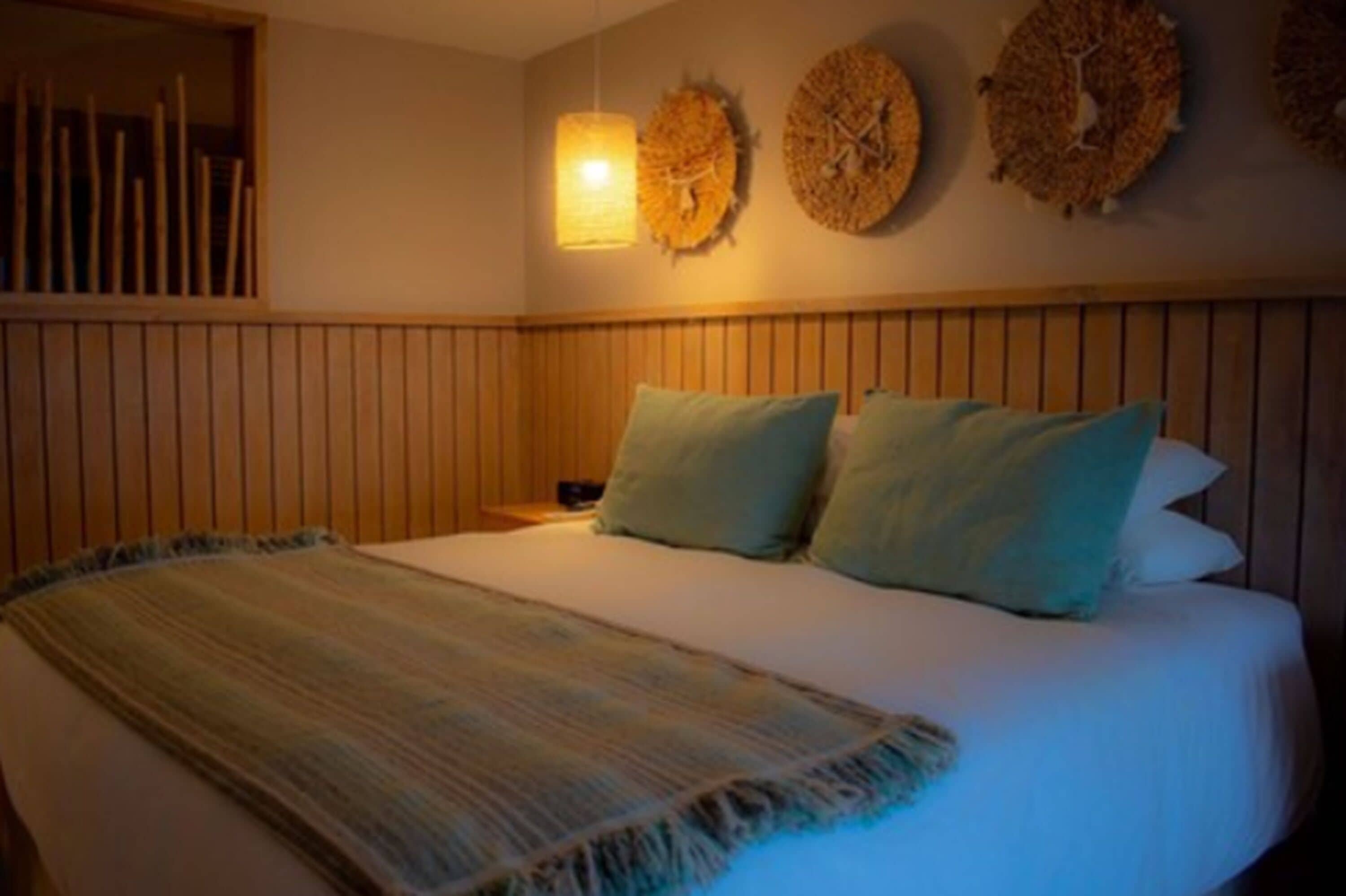 A bed with a striped blanket, two pillows, and a wooden headboard.