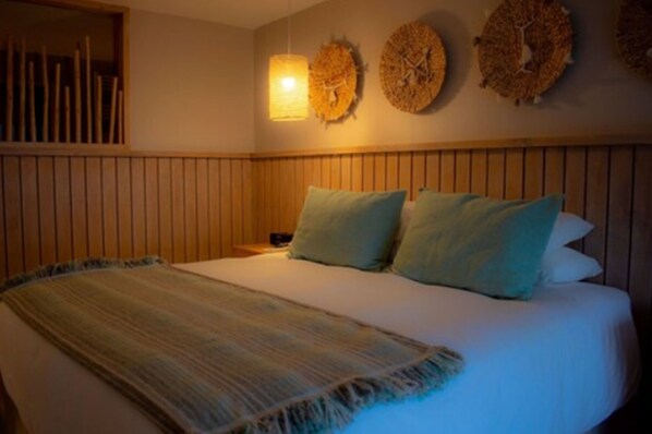 Una cama con un edredón a rayas, dos almohadas y un cabecero de madera.