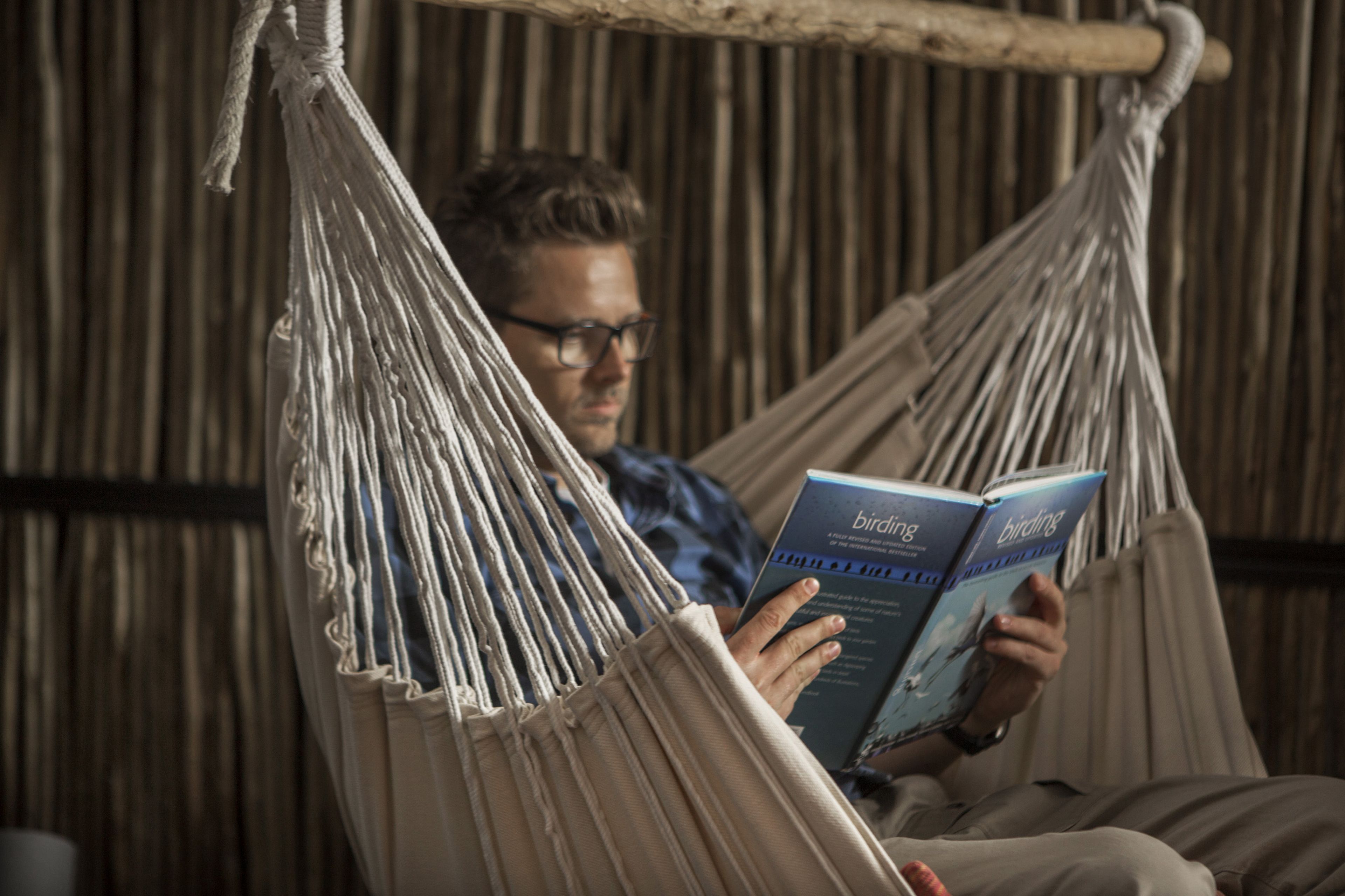Une personne est en train de lire un livre dans un hamac.