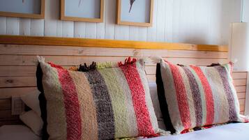Una cama con almohadas a rayas y tres plumas enmarcadas en la pared.
