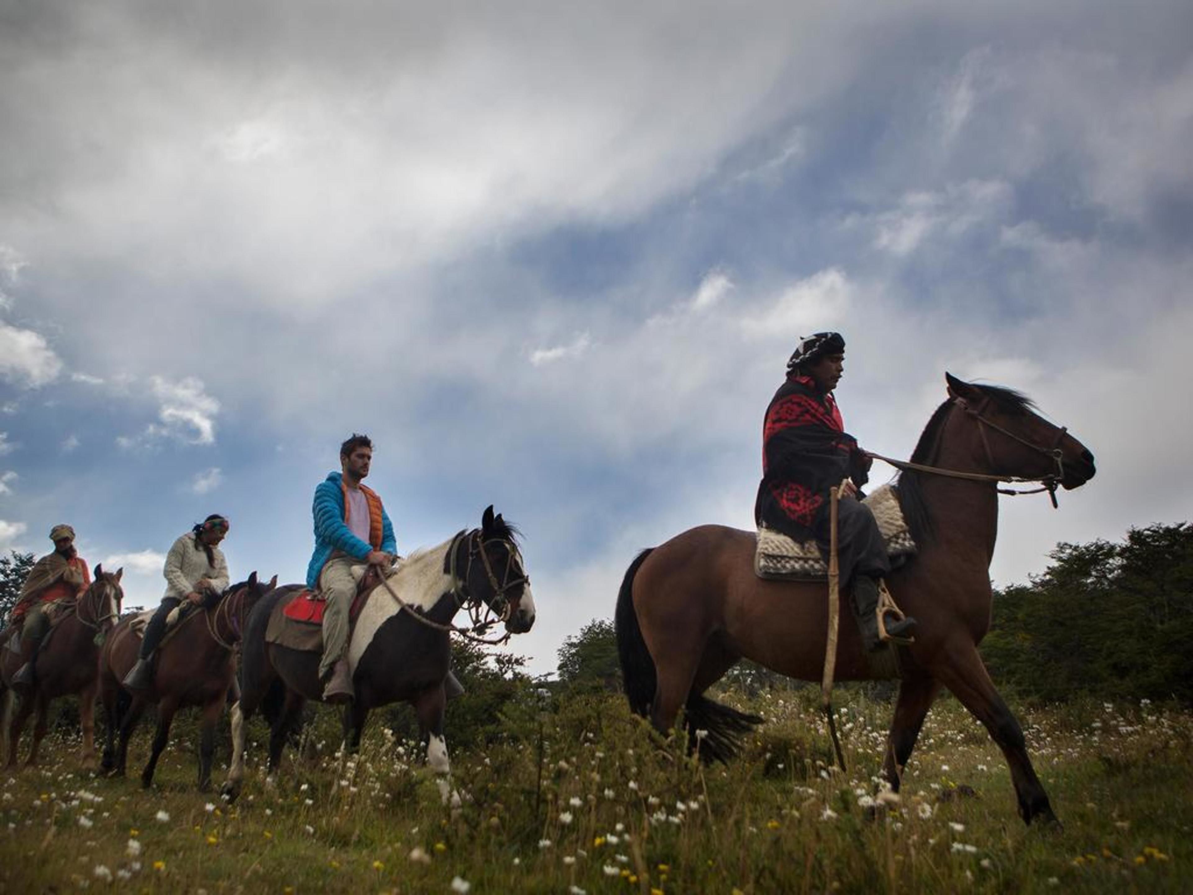 Un grupo de personas montando caballos en un campo bajo un cielo nublado.