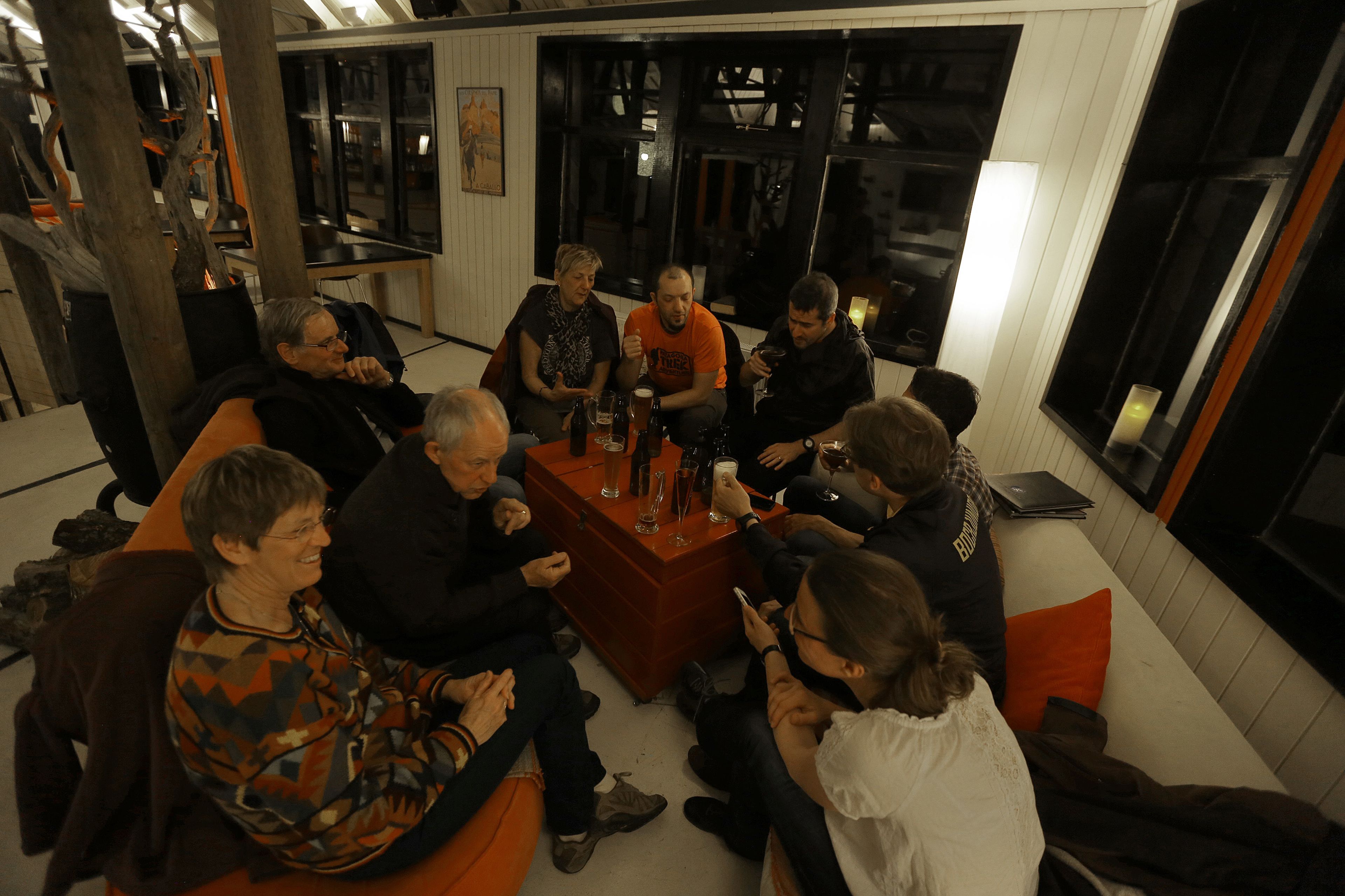 A group of people seated around a wooden table in a room with white walls and large windows.