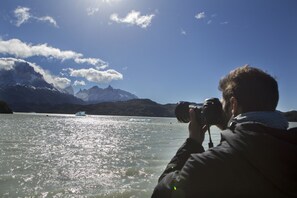 A person taking a photograph of a lake with mountains in the background. - Noi Indigo Patagonia (Natales)