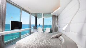 A modern bedroom with a large bed, a TV, and a balcony with a view of the sea. - Son Moll Sentits Hotel & Spa (Capdepera)