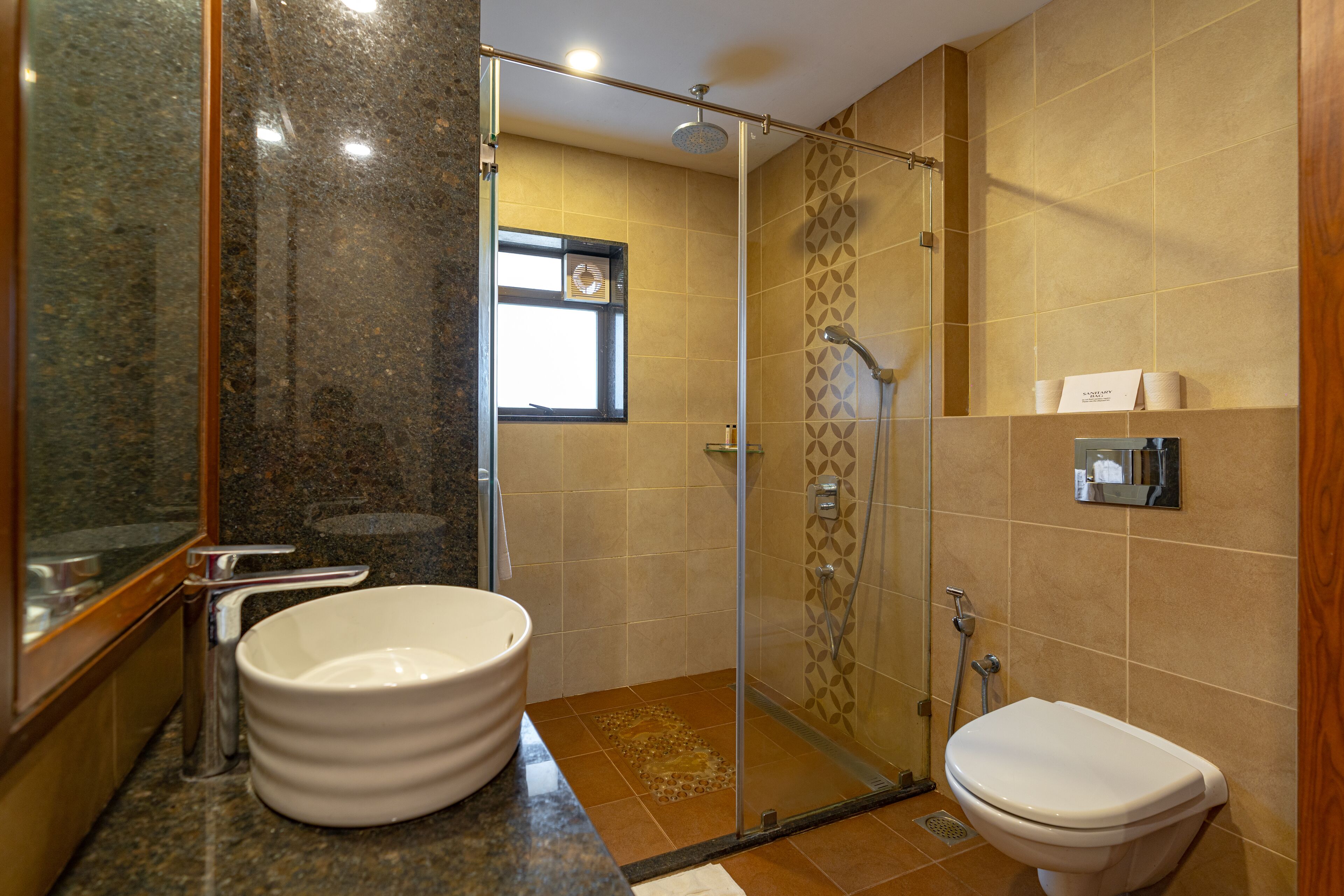 Een badkamer met een douchecabine van glas, een witte wastafel en een toilet.