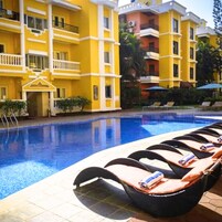 A hotel with a pool area, including lounge chairs and a clear blue pool.