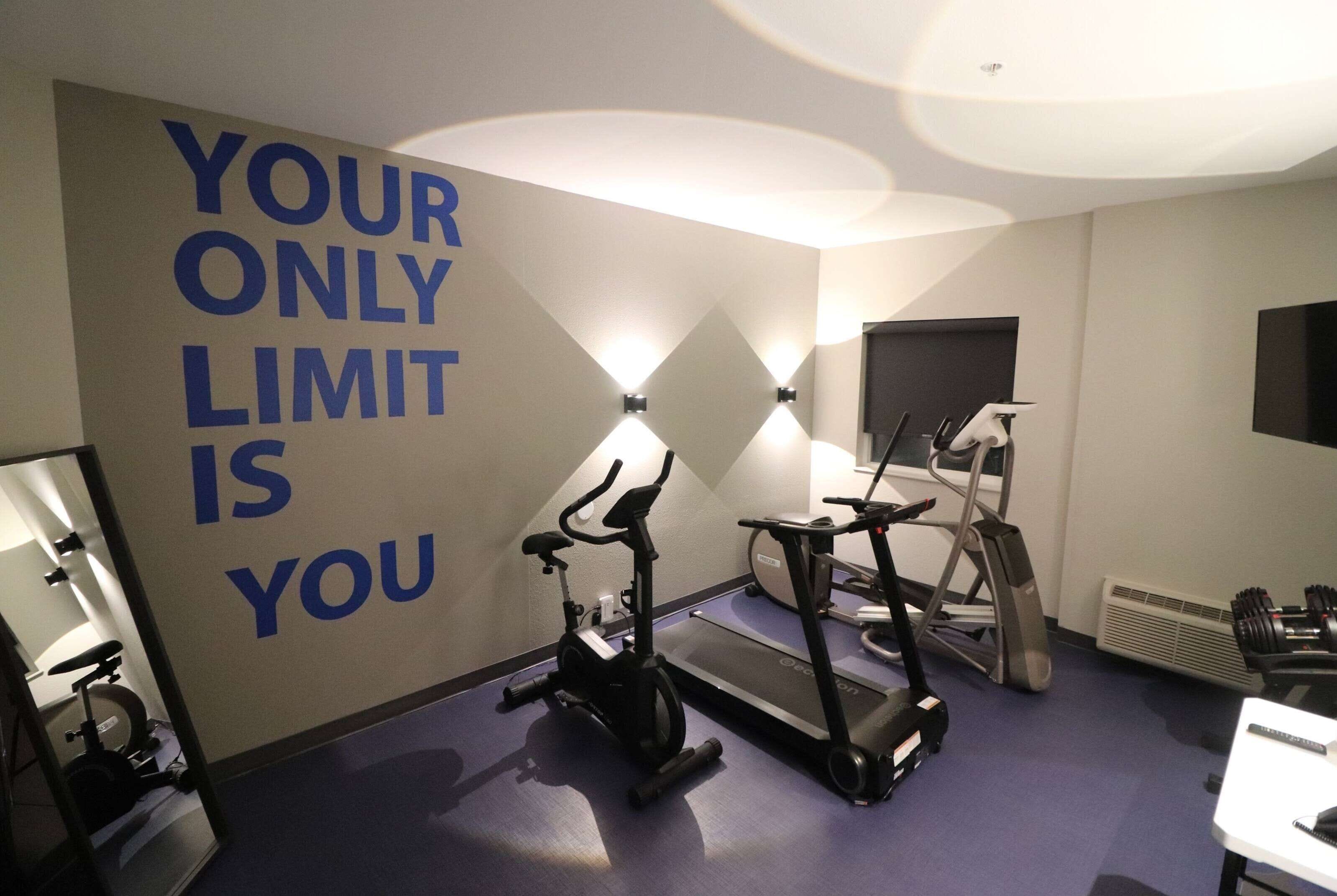 Et fitnesscenter med træningsudstyr og motiverende tekst på væggen.