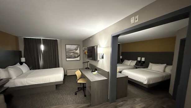 A hotel room with two beds, a desk, a chair, a TV, and a painting on the wall. - Days Inn by Wyndham Stony Plain (Stony Plain)
