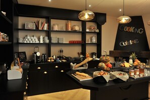 A kitchen area with a black countertop, shelves with kitchenware, and a sign that reads "COOKING CUISINE". - Mercure Paris Saint Cloud Hippodrome (Saint-Cloud)