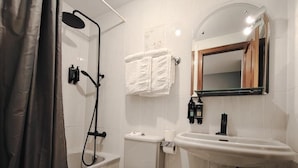 A bathroom with a shower, toilet, sink, and a mirror.