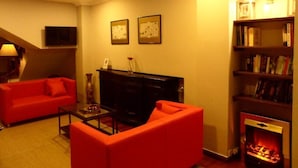 A living room with a red sofa, a black entertainment unit, a fireplace, and a bookshelf.