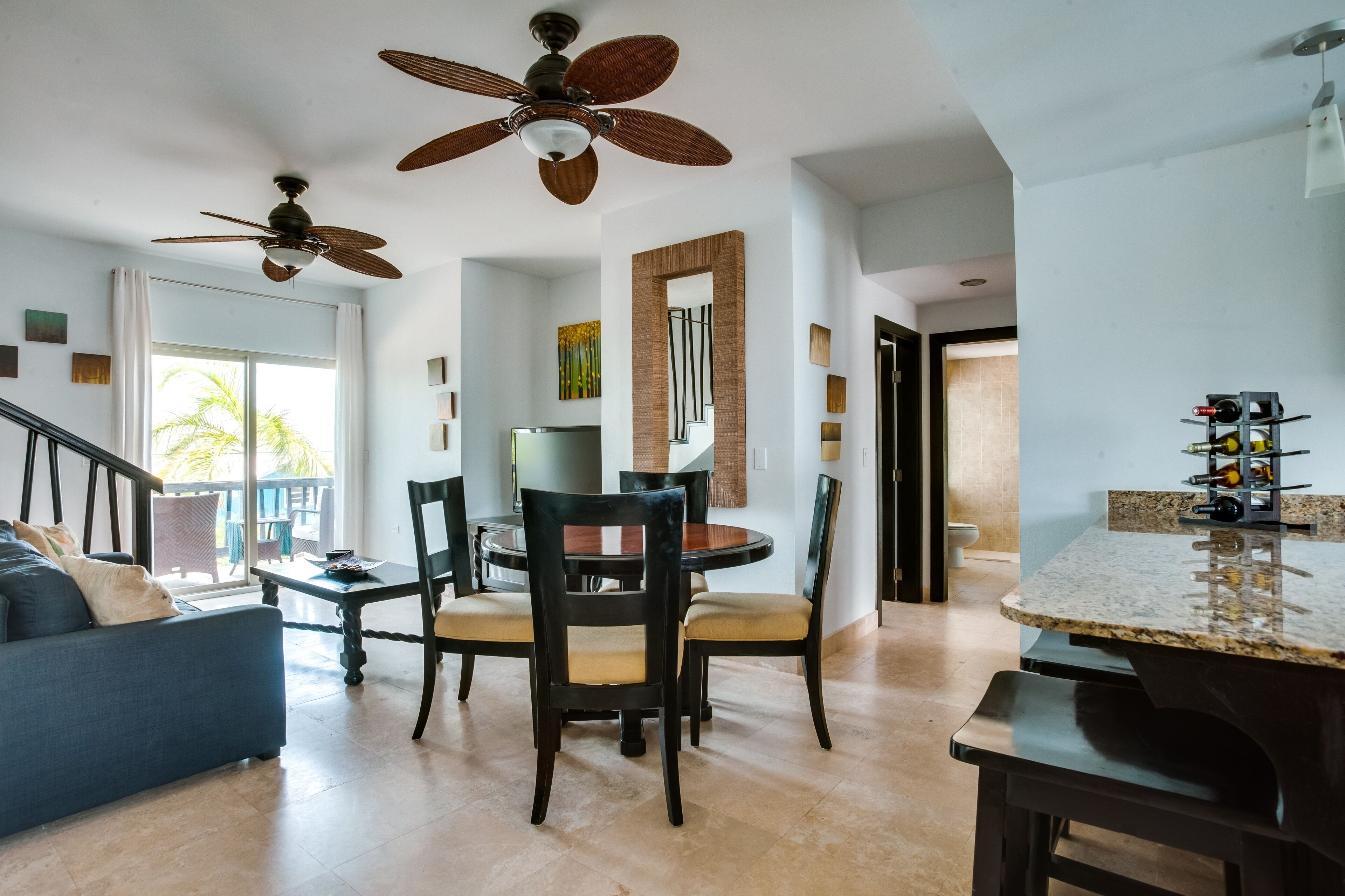 A spacious living area with a dining table, chairs, and a ceiling fan.