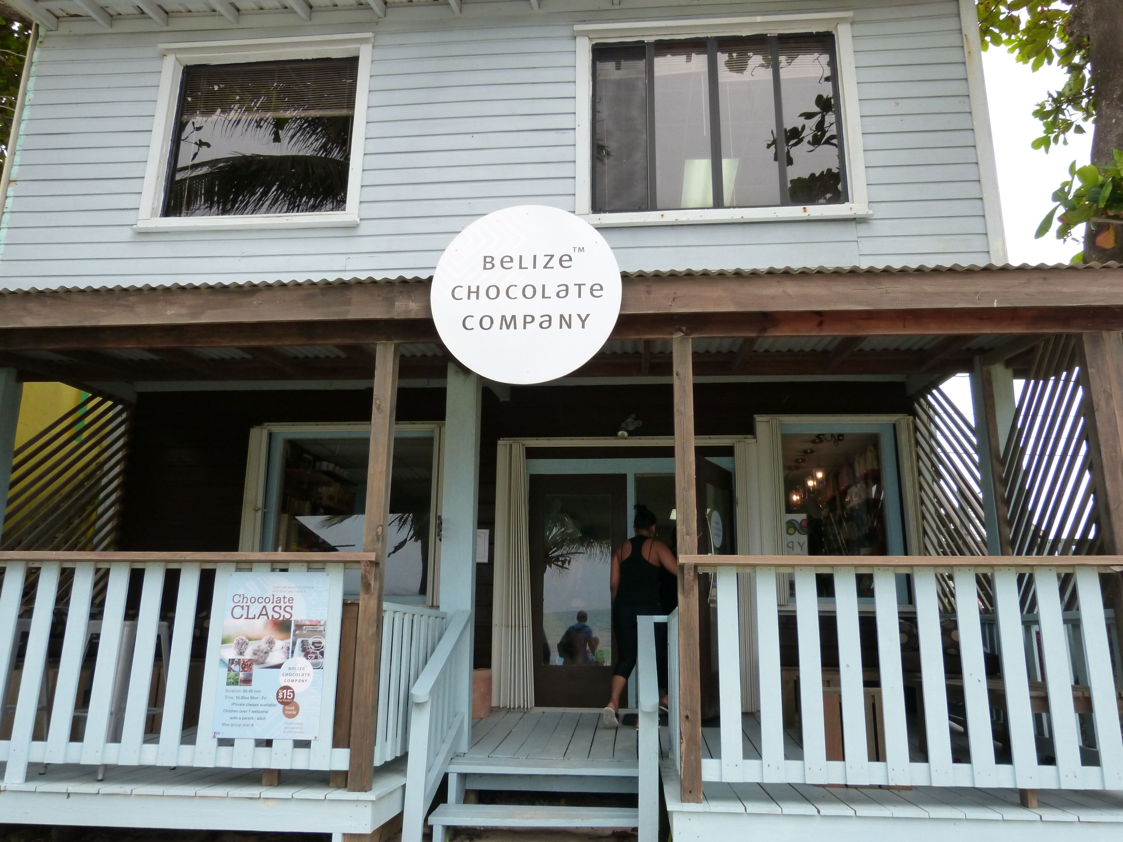 A two-story building with a porch and a sign for Belize Chocolate Company.