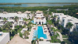Un resort con piscina central, varias construcciones y exuberante vegetación circundante.