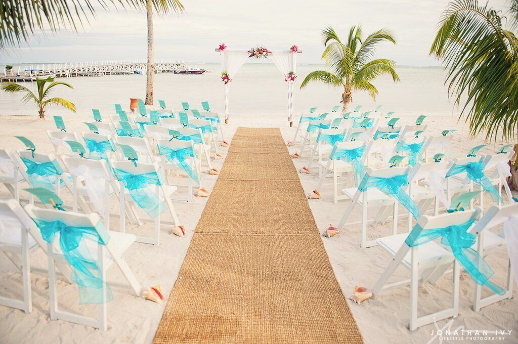 A beach wedding setup with white chairs and a central aisle.