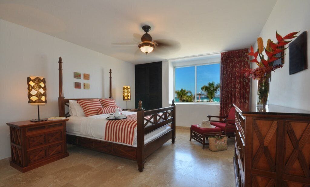 A bedroom with a wooden bed, nightstands, a ceiling fan, a window with a view, and a red chair.