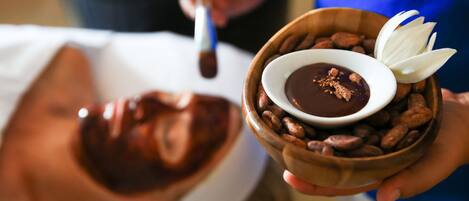 Una persona sosteniendo un tazón de chocolate con una flor y nueces.
