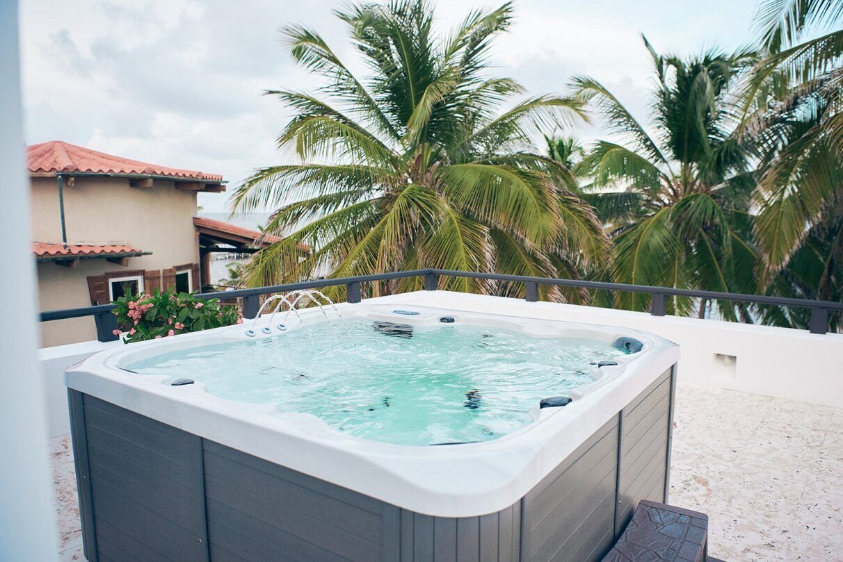 Un jacuzzi en un balcón con palmeras al fondo.