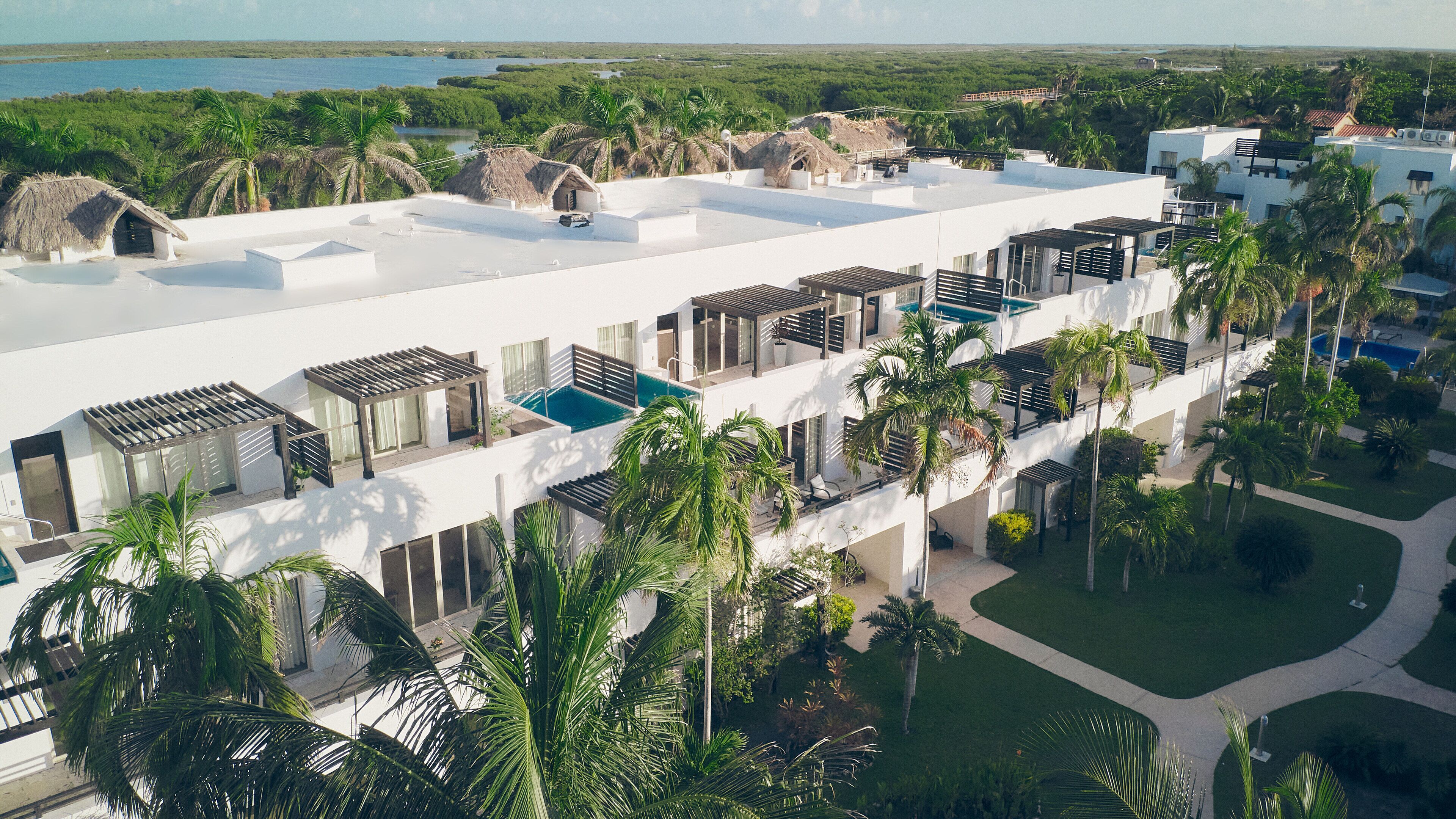 Resort com vários edifícios brancos, piscina e palmeiras.