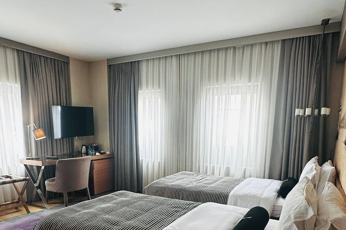 Une chambre d’hôtel avec deux lits, un bureau, une télévision et une petite table.