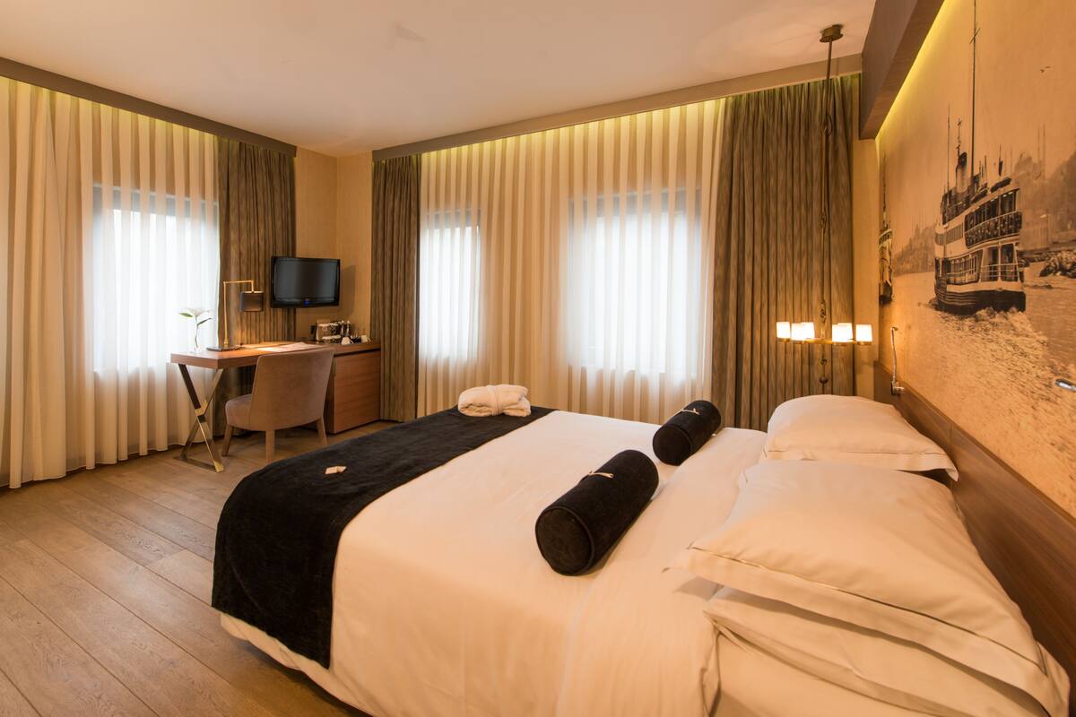 Une chambre d’hôtel avec un grand lit, un bureau, une chaise et un téléviseur.