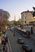 Un tranvía en una calle curva con peatones y coches.