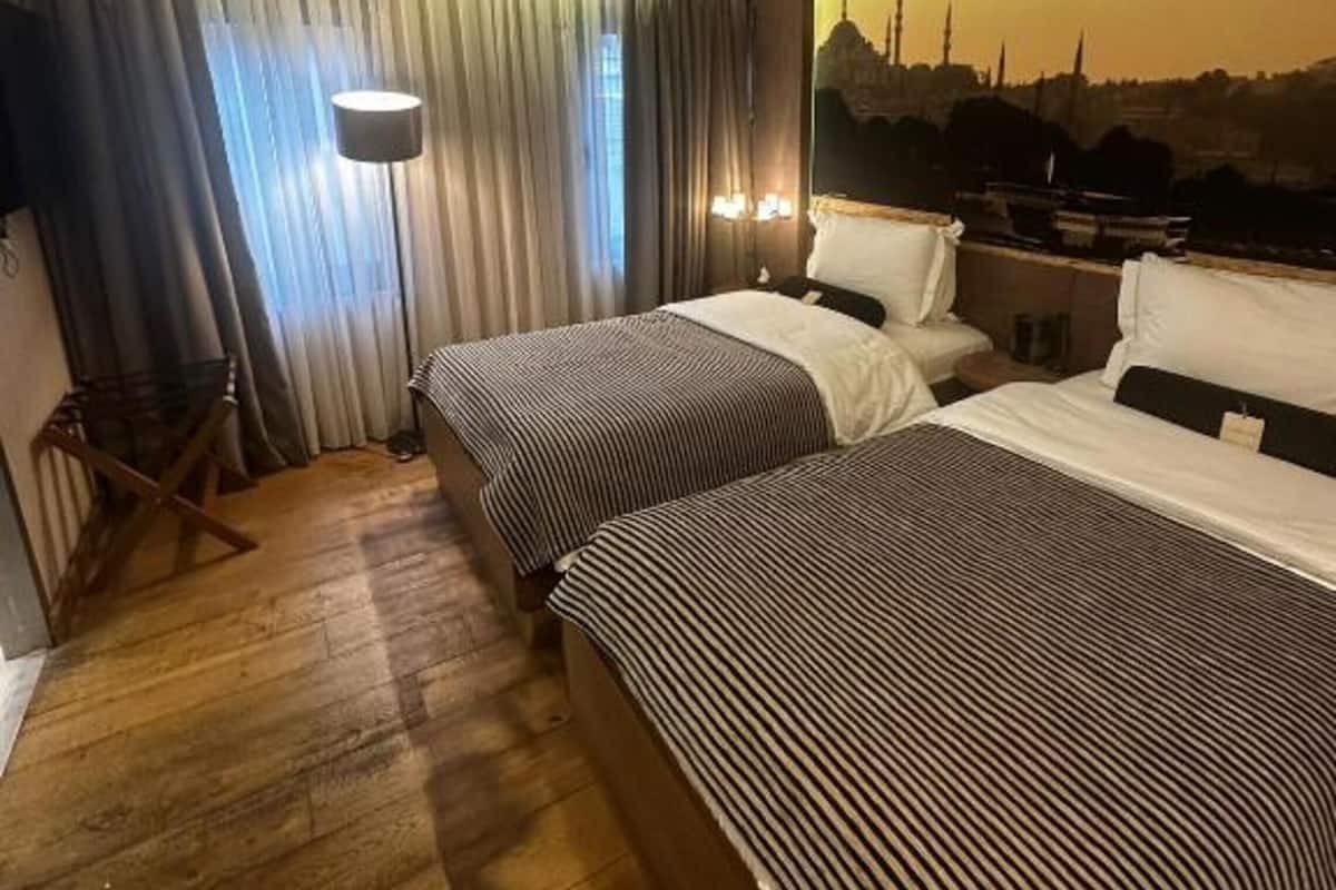 Une chambre d’hôtel avec deux lits, une vue sur la ville, un plancher en bois et un rideau.