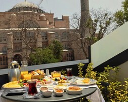 A table set with breakfast items, including eggs, toast, and fruit, overlooking a historic building with domes and arches.