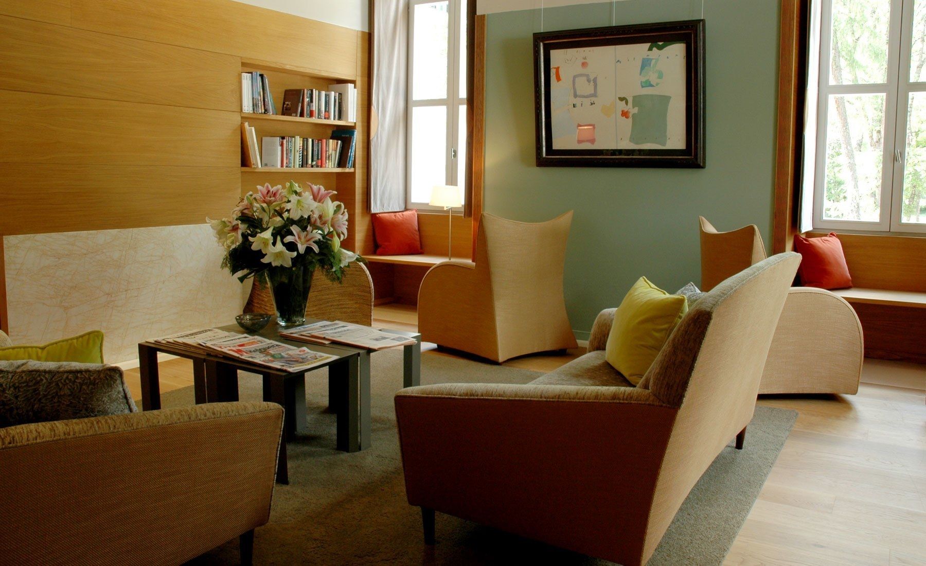 Een moderne woonkamer met een bank, fauteuils, een salontafel en een boekenkast.