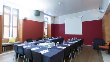 Una sala conferenze con un lungo tavolo, sedie, uno schermo per proiettore e un'ampia finestra.